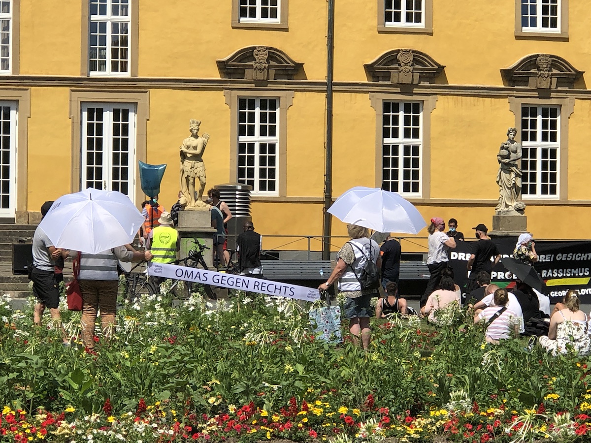 Barockes Schloss, bunte Blumen und Omas gegen rechts mit Sonnenschirmen