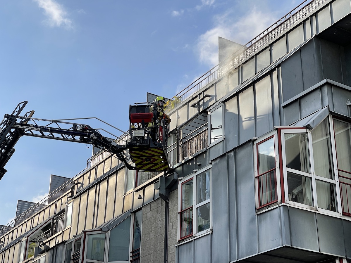 Ein Feuerwehrmann versucht auf den Balkon der brennenden Wohnung zu gelangen