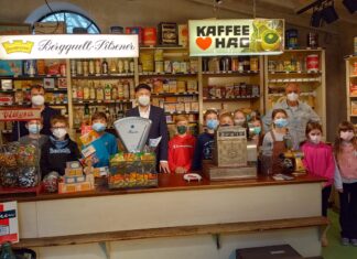 Jan Tönnies (hinten links), Nils-Arne Kässens und Dr. Thorsten Heese stehen mit 4. Klässlern der Grundschule Eye im Tante-Emma-Laden. / Foto: Brockfeld