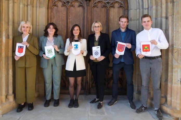 Die aktuellen Städtebotschafter von Osnabrück mit Oberbürgermeisterin Katharina Pötter: (von links) Abigaël Landreau, Rosie Jones, Irmak Uzunoğlu, Katharina Pötter, Wisse Hendriksma und Aleksandr Sindeev jeweils mit den Fähnchen ihrer Stadt. / Foto: Swaantje Hehmann