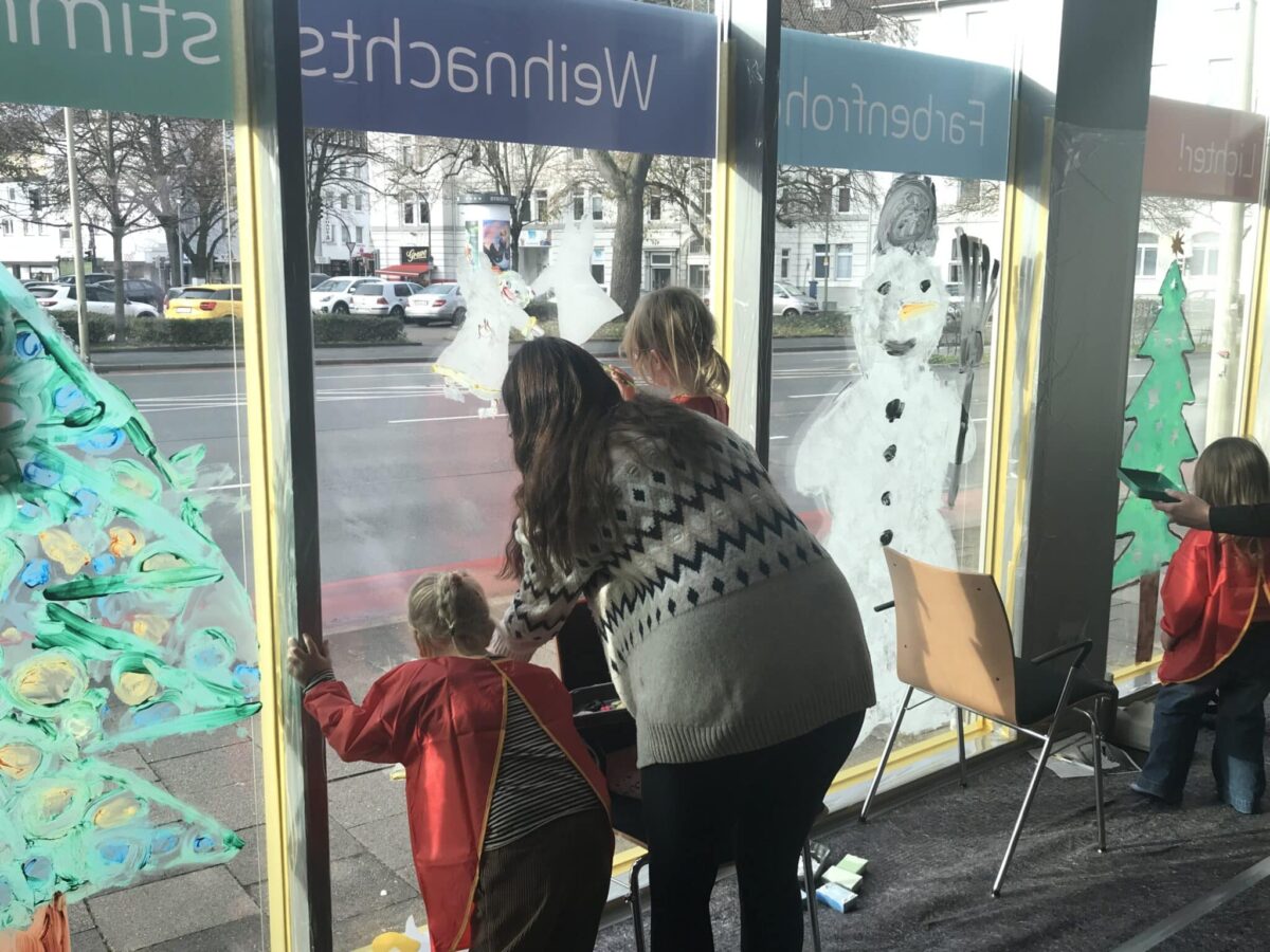 Kinder bemahlen mit Erzieherin die Fenster des Westenergie-Standorts am Goethering. / Foto: Burrichter