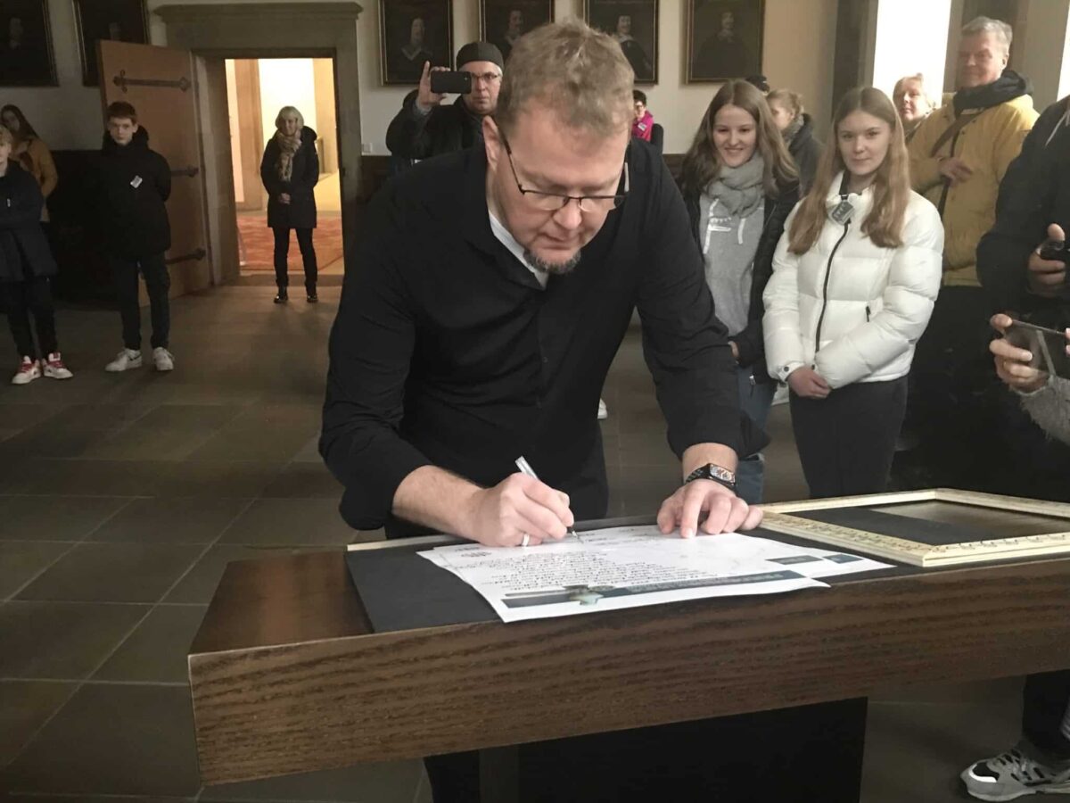 Schulleiter Matthias Wocken unterzeichnet die Urkunde im Friedensaal des Rathauses. / Foto: Burrichter