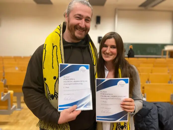 (von links) Der Künstler Leon Hinrichsmeyer und die Künstlerin Clara Uhlemann von der Uni Osnabrück haben die mit je 2.000 Euro dotierten Ingeborg-Sieber-Kunstförderpreise erhalten sowie als weitere Trophäe einen Schal von Künstlerin Anna Haifisch, der als Edition von der Kunsthalle Osnabrück herausgegeben wurde. / Foto: Uni Osnabrück