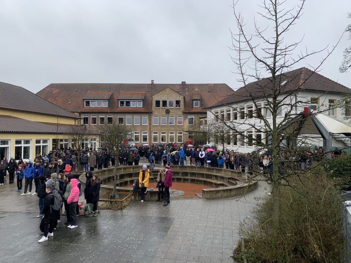 Trotz des regnerischen Wetters haben zahlreiche Schülerinnen und Schüler am Trauerflashmob auf dem Schulhof der Ursulaschule teilgenommen. / Foto: Emrich