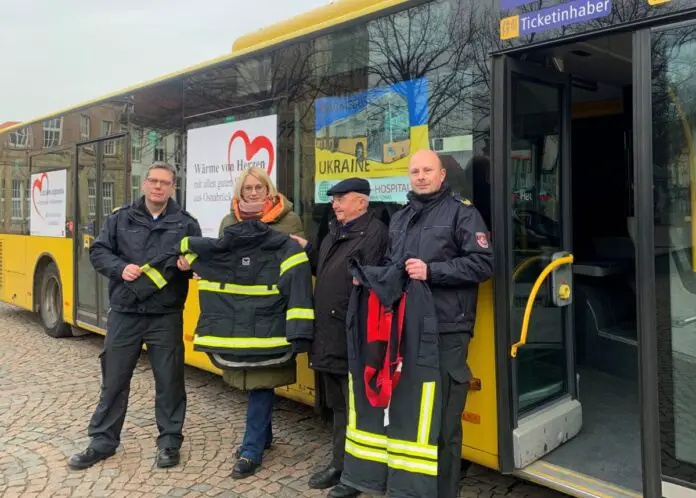 (von links) Dietrich Bettenbrock, Oberbürgermeisterin Katharina Pötter, Reinhart Richter und Frank Jurke bei der Übergabe der Feuerschutzkleidung vor einem der Wärmebusse. / Foto: Emrich