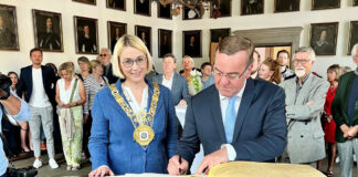 Verteidigungsminister Pistorius trägt sich ins Goldene Buch ein, links neben ihm Oberbürgermeisterin Katharina Pötter