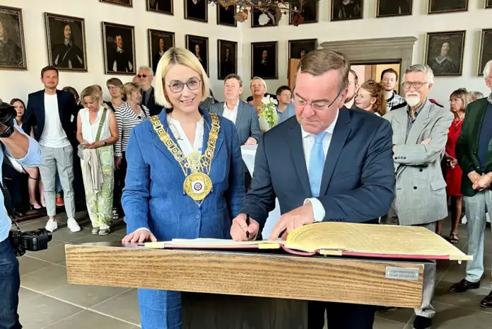 Verteidigungsminister Pistorius trägt sich ins Goldene Buch ein, links neben ihm Oberbürgermeisterin Katharina Pötter