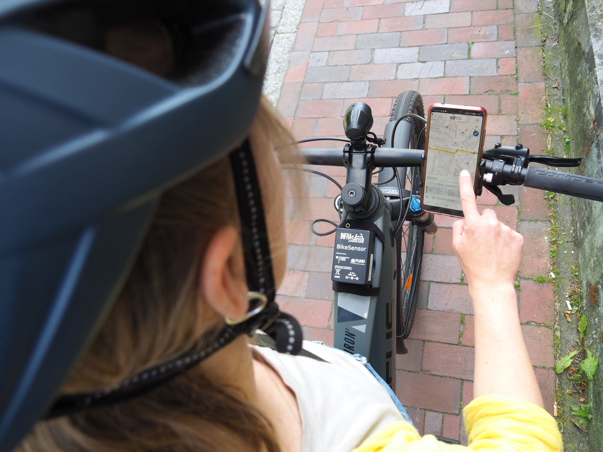 Eine Radfahrerin, die den Infrasense-Sensor an ihrem Fahrrad montiert hat, betrachtet die Daten in der BIQEmonitor-App. / Foto: Jayson Libdan Lázaro, mein-dienstrad.de