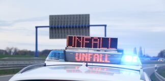 Streifenwagen der Polizei mit Blaulicht und Textwarnung "Unfall"